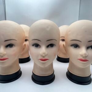 Row of bald mannequin heads with painted facial features, arranged in a display for makeup practice or display purposes.