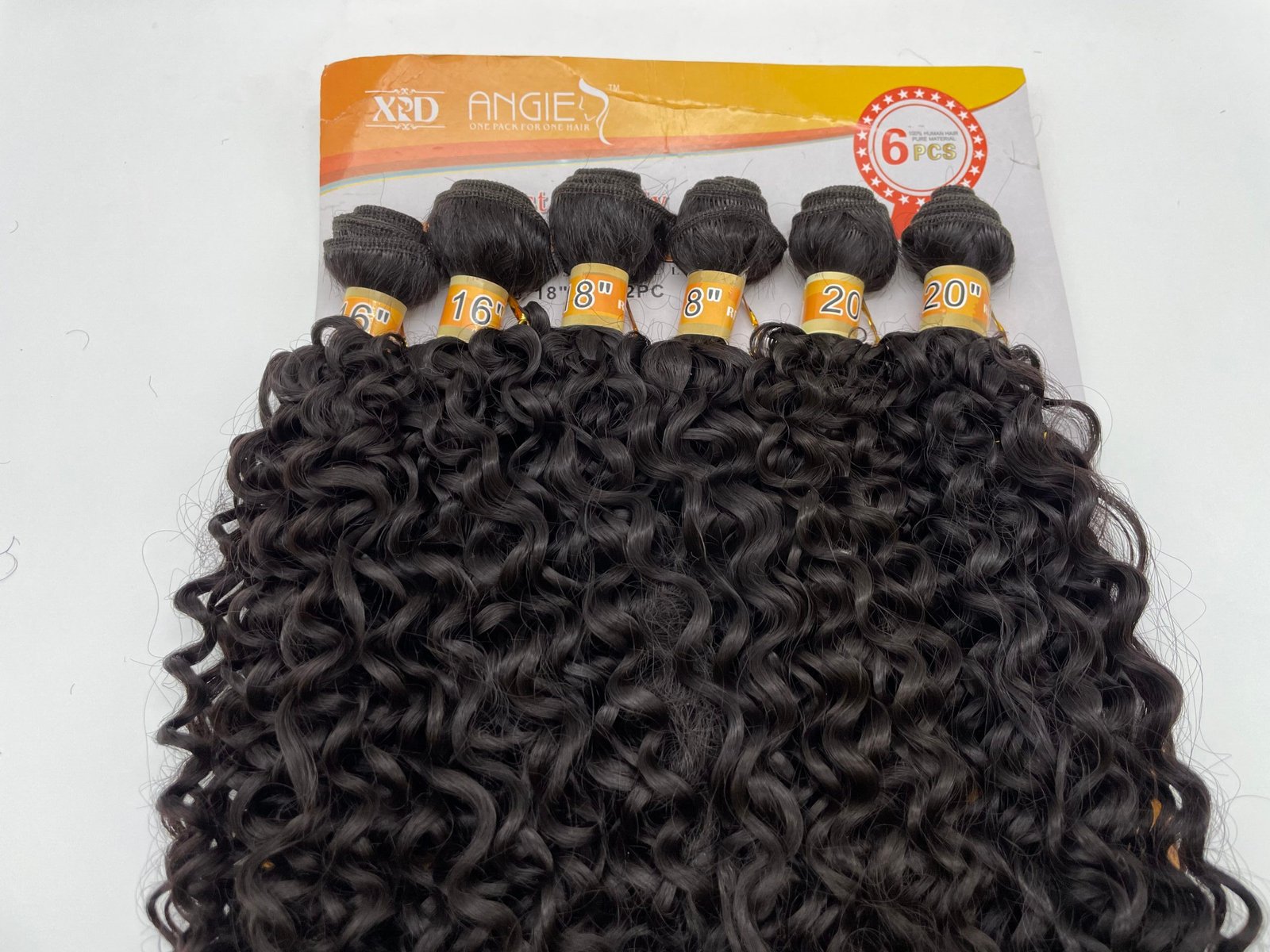 Close-up of glossy black curly hair extensions bundled together with orange label tags on a display card.