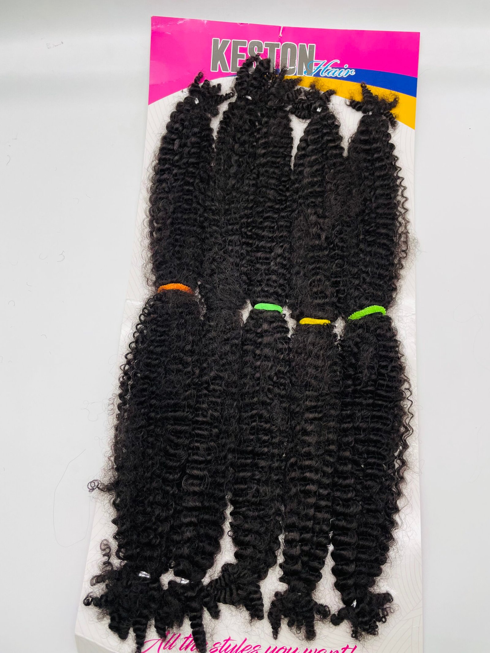 Package of long, curly black hair extensions displayed on a pink and yellow product card labeled Keston Hair