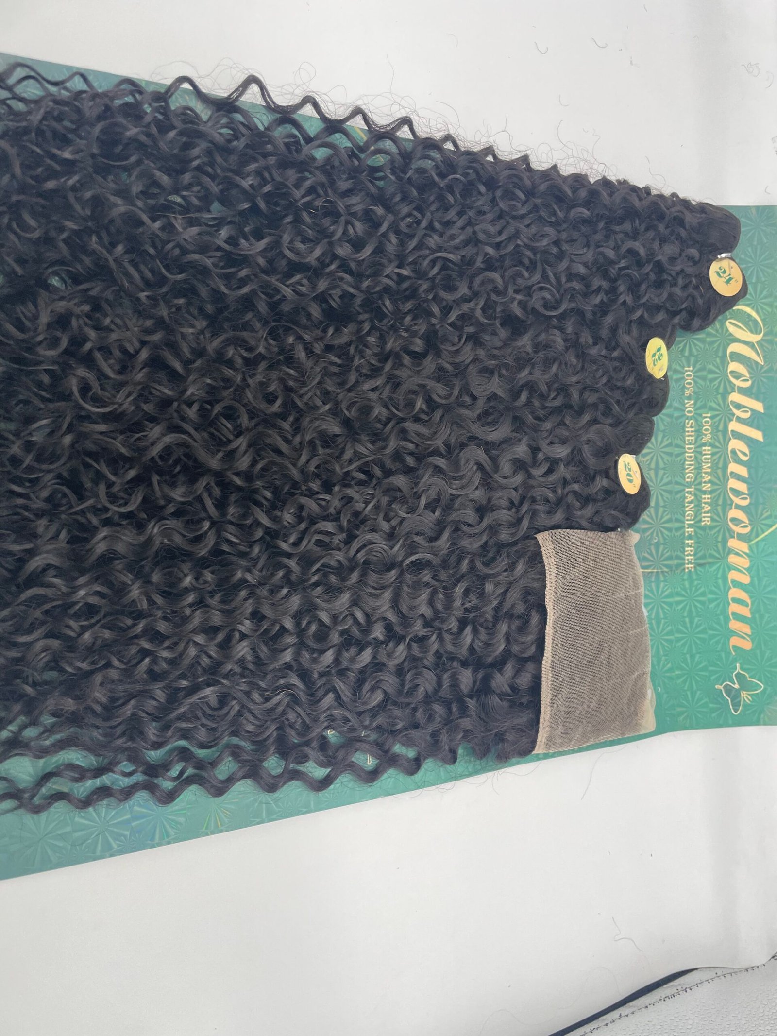 Close-up of multiple black curly hair extensions arranged in strands on a green display card.