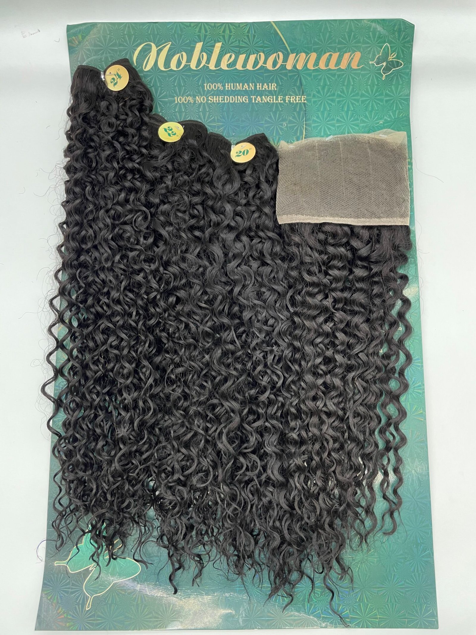 Curly black hair extensions laid on a teal display card, showing long, tight curls and wefts.