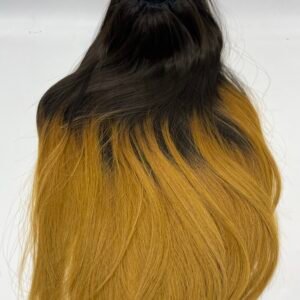 Back view of a person with long two-tone hair (dark roots fading to orange) secured with a black ruffle scrunchie at the crown of the head.