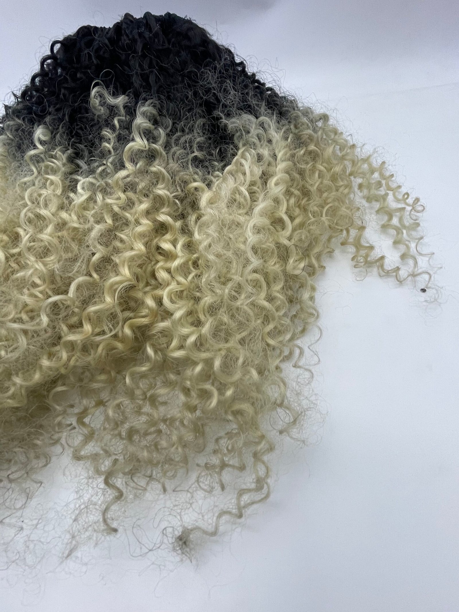 Two-tone curly hair with black roots fading to platinum blonde curls