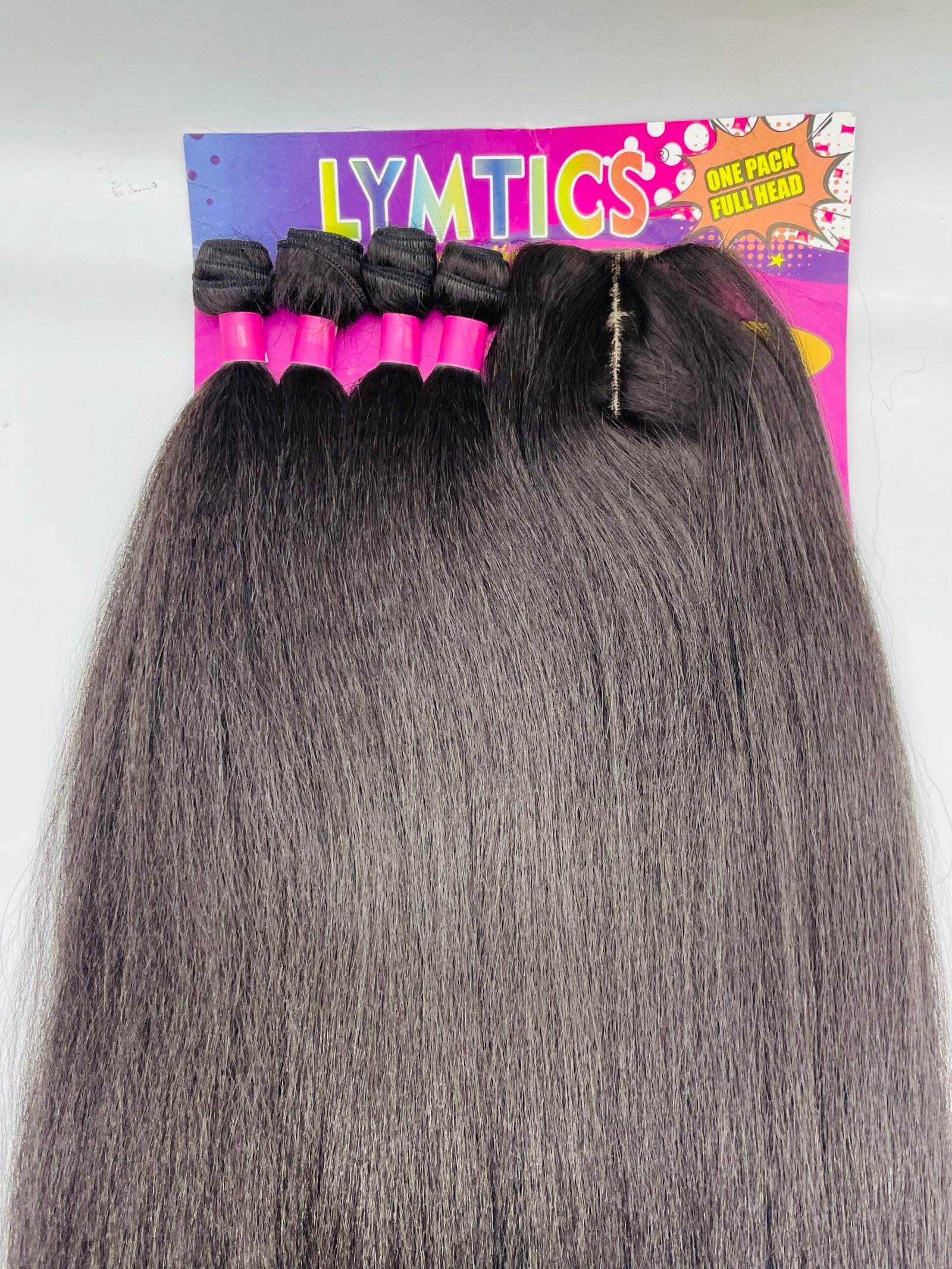 Row of dark hair extension bundles with bright pink bands laid on a colorful display board