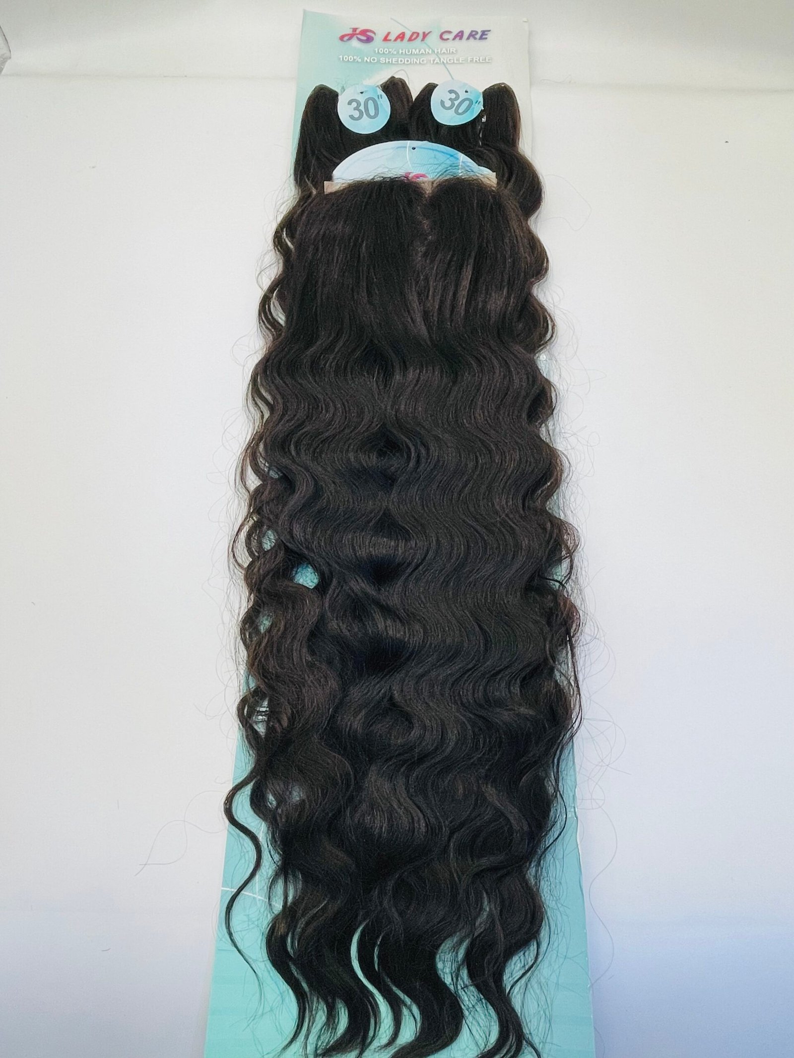 Back view of a long dark wavy hair wig on a light blue display stand against a white wall, showing natural wave pattern and length.