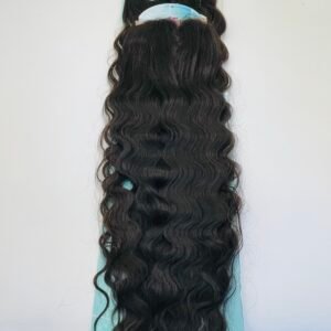 Long dark wavy hair extensions displayed on a turquoise board, viewed from behind.
