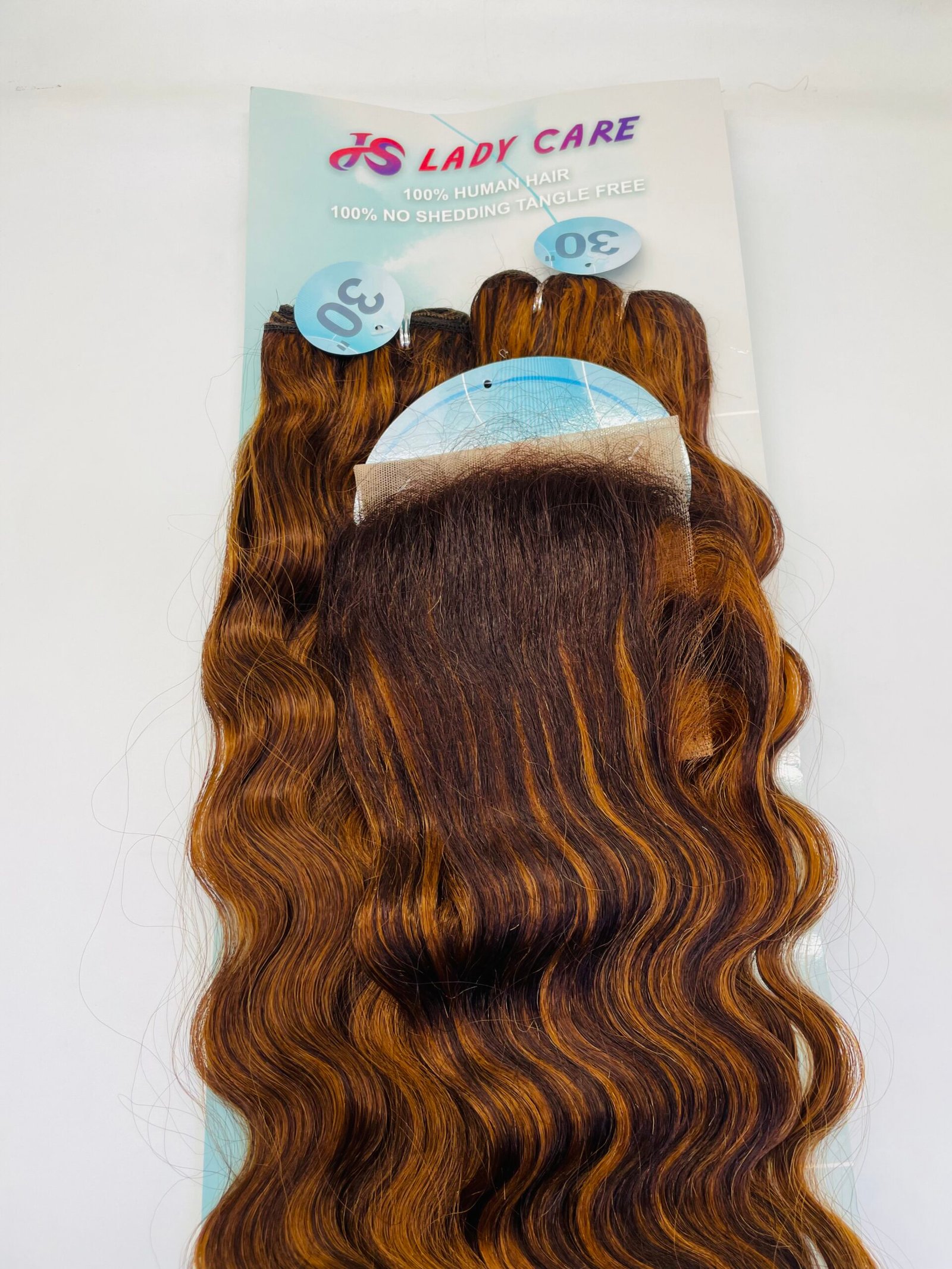 Wavy reddish-brown hair extensions laid over a promotional card reading 'Lady Care' and '100% human hair'.