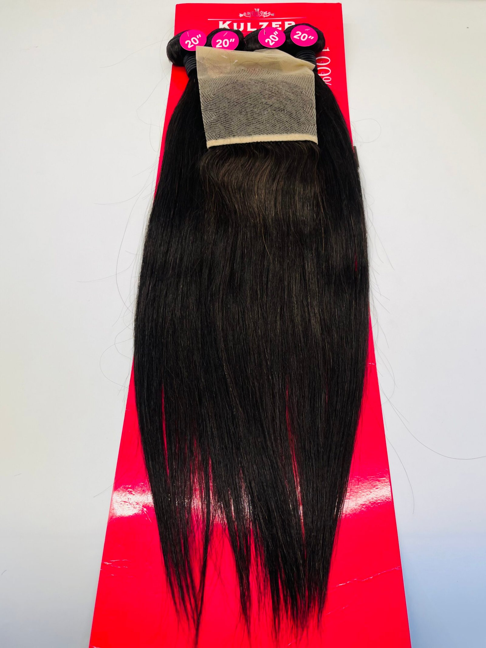 Long black hair extensions attached to a bright red card showing 20" length labels