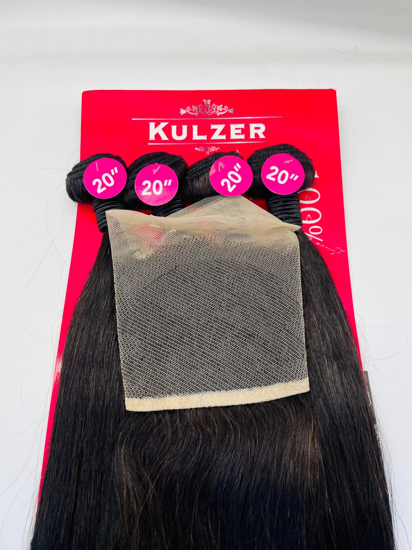 Product image of hair extensions laid over a red Kulzer packaging with four black wefts labeled 20" in pink circles and a beige mesh wrap over the hair