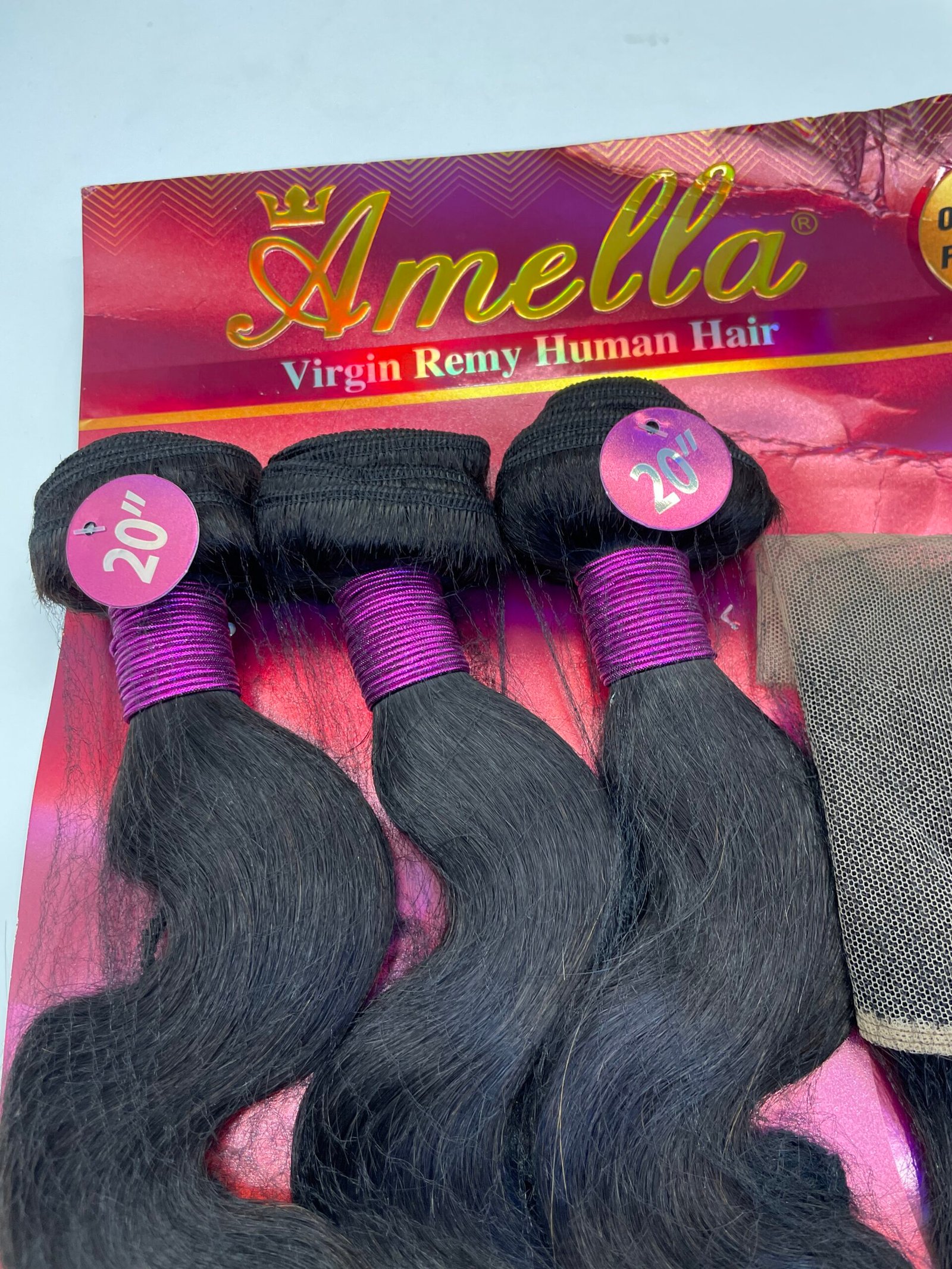 Bundles of long black hair extensions with pink wrap and 20" tags on a pink Amella packaging window, labeled Virgin Remy Human Hair.