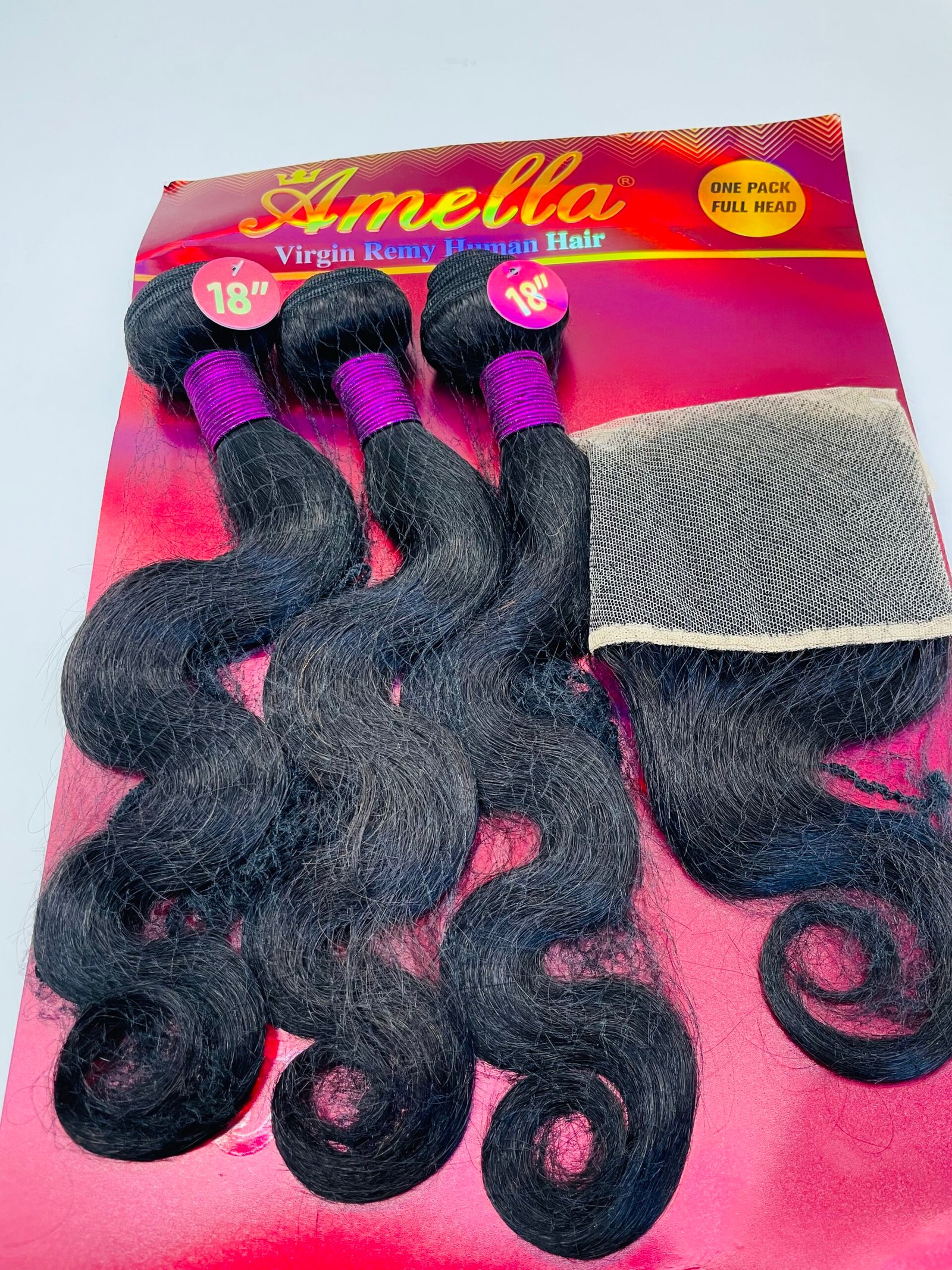 Pack of black 18-inch hair extensions on a pink card with purple bands and a mesh panel, labeled '18' inches' on each bundle's tag