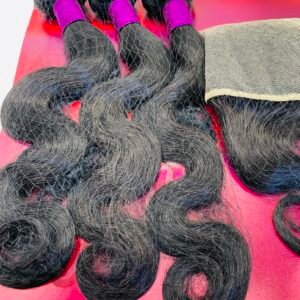 Bundles of long black hair extensions tied with bright pink bands, laid on a red display background showing 18" length