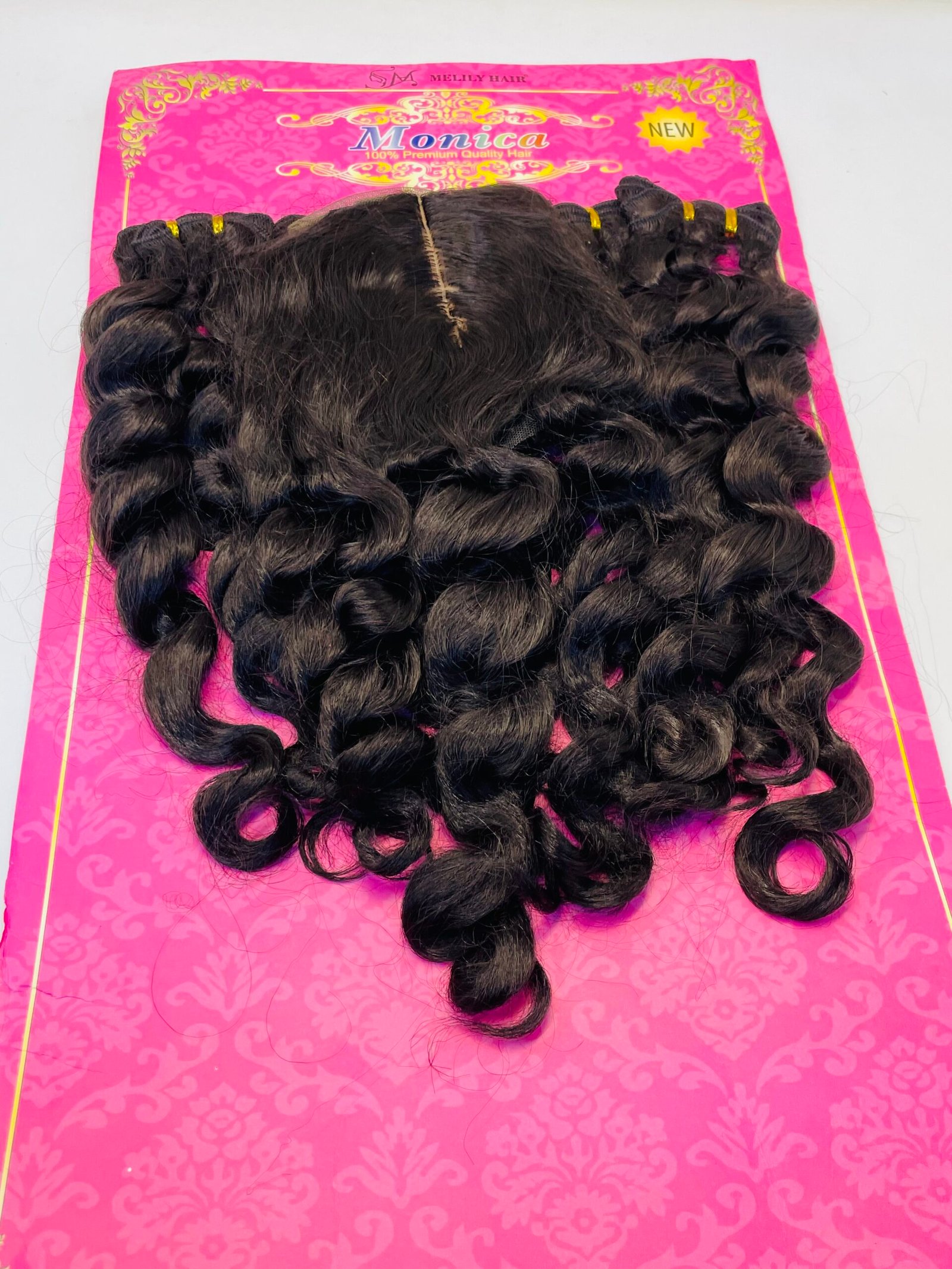 Dark brown curly hair extensions displayed on a bright pink display card