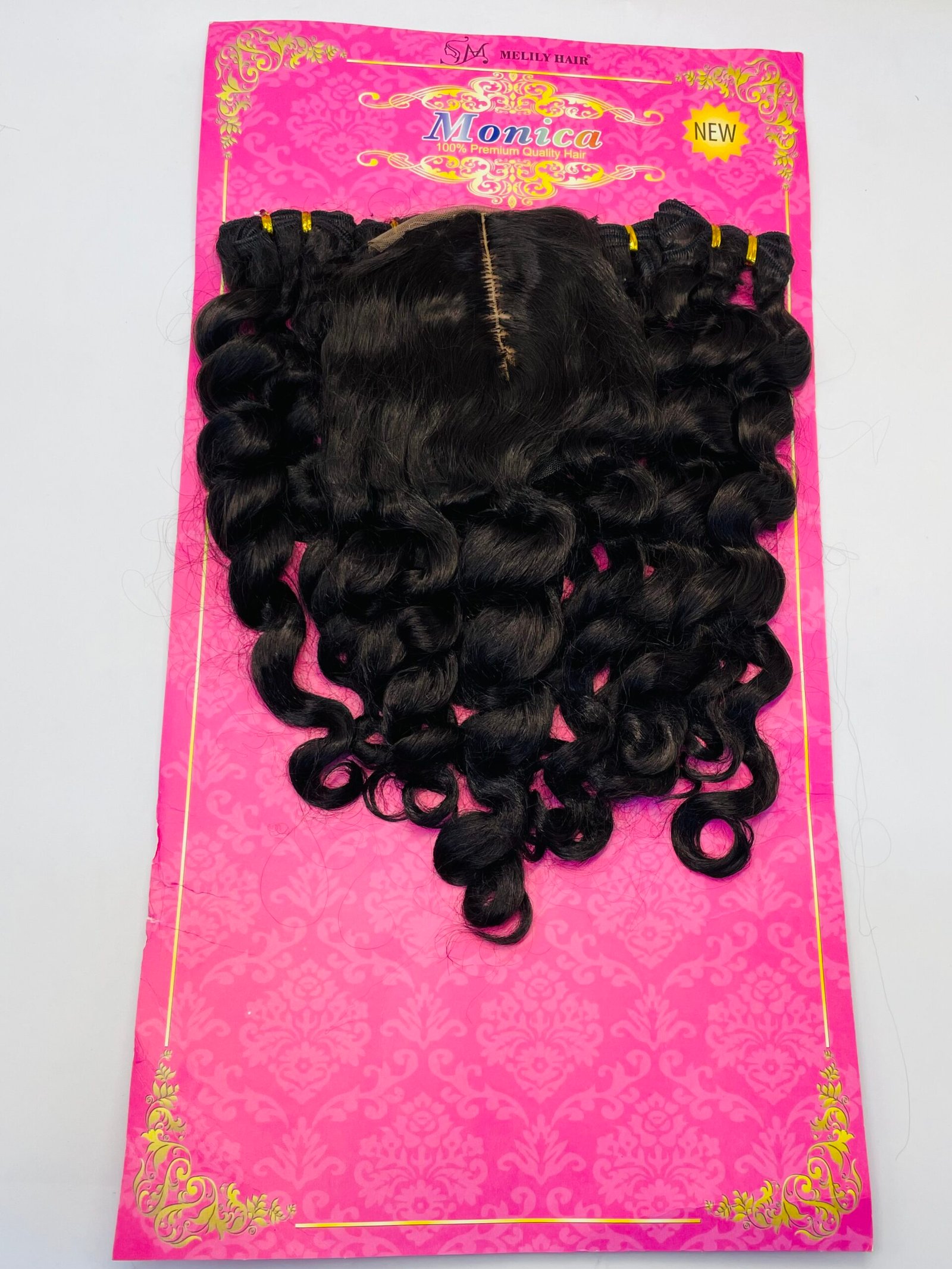Bundle of black curly hair extensions attached to a bright pink card with gold decorative patterns and 'Monica' branding.