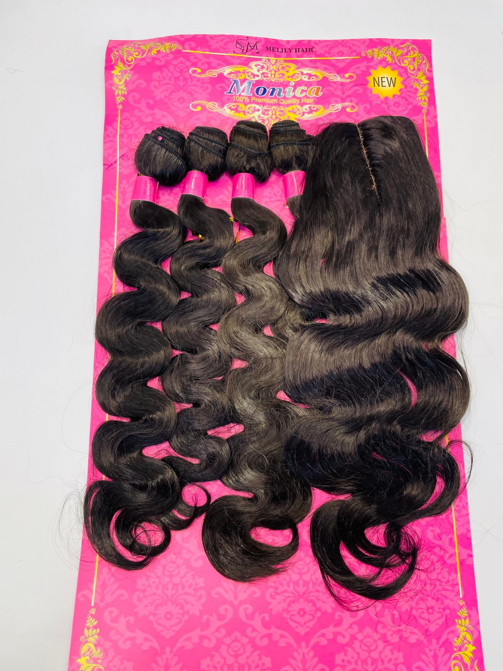 Dark brown to black curly hair extensions on a bright pink display card labeled 'Monica' with gold decorative pattern and 'New' tag (hair bundles shown).