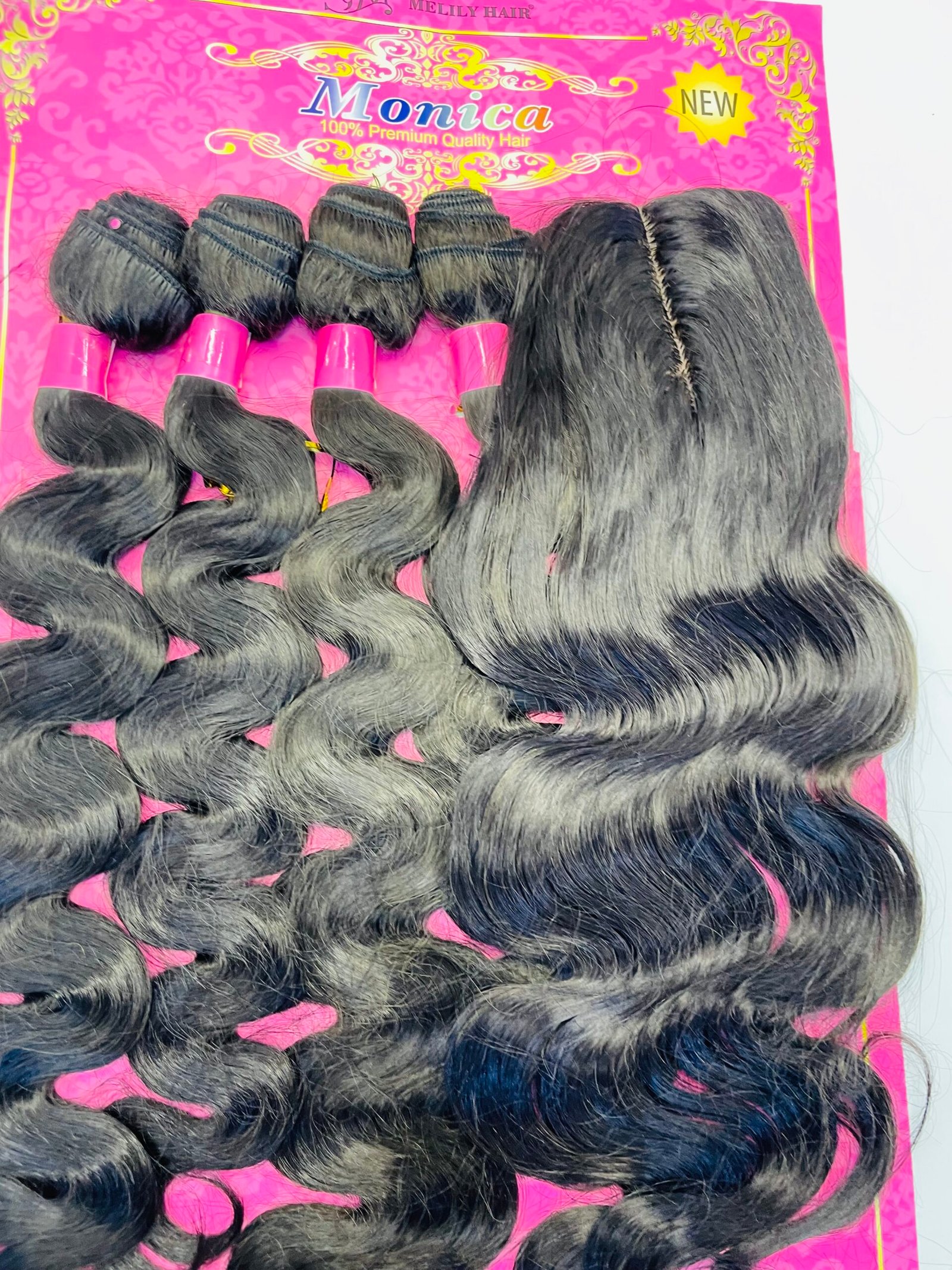 Rows of black hair extensions with pink bands laid on a bright pink backdrop labeled 'Monica' packaging.