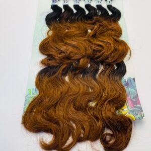 Six bundles of wavy hair extensions on a pastel display card, fading from black at the roots to copper brown at the ends.