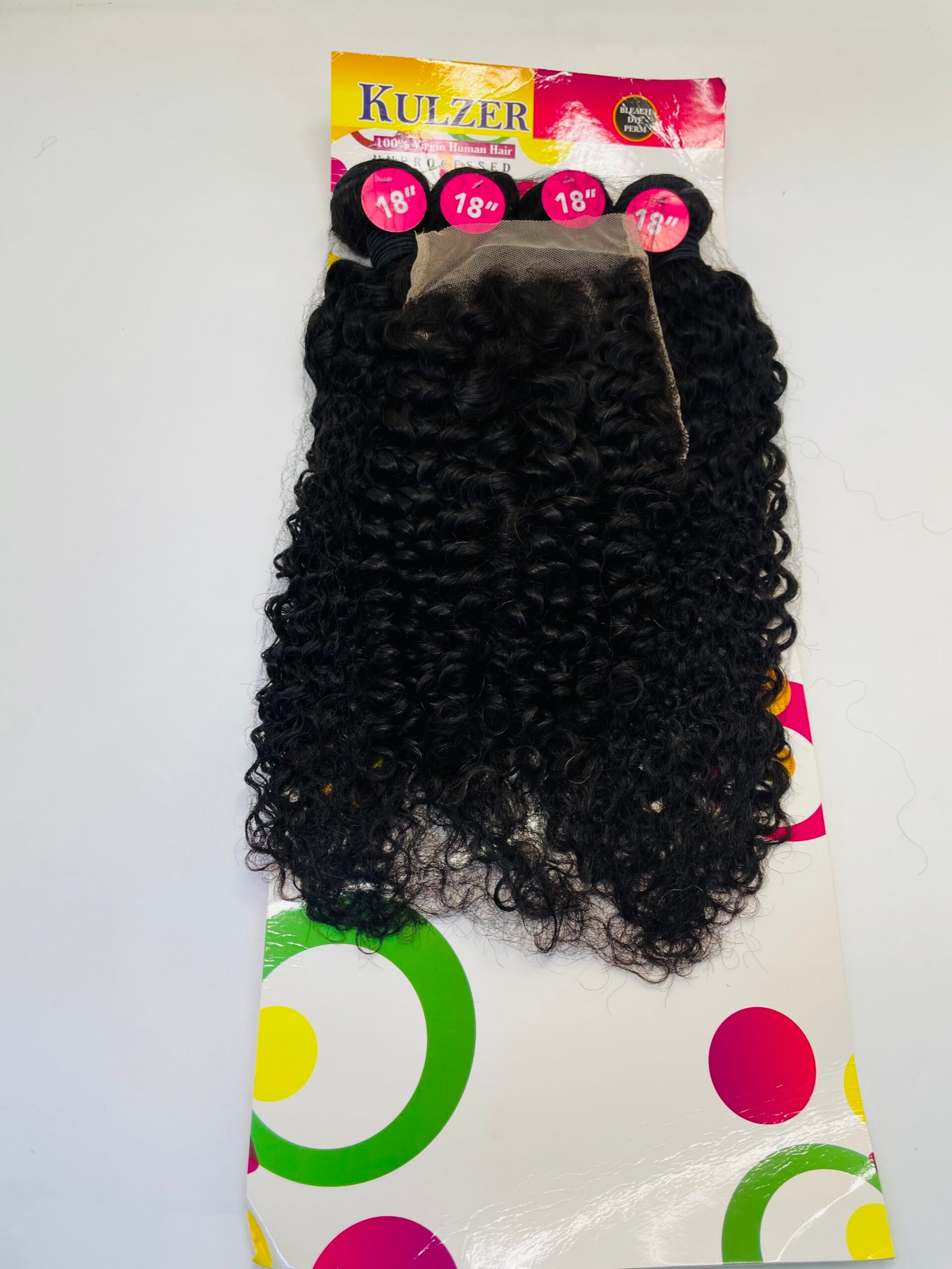 Rear view of long, tightly curled black hair extensions attached to a colorful packaging board with pink circles labeled 18".