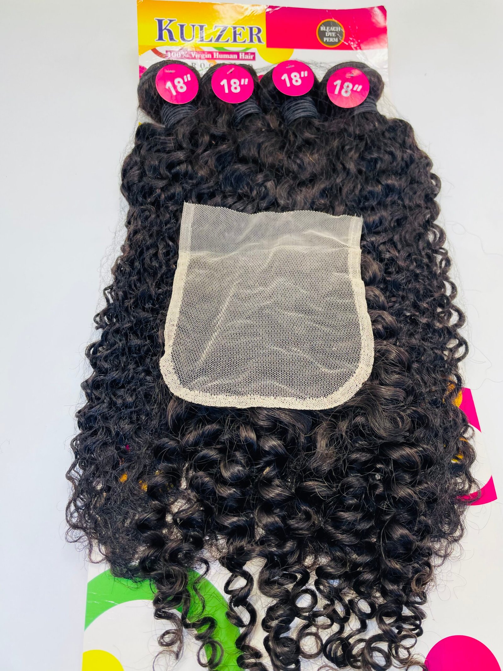 Back view of curly black hair extensions with a beige wig cap attached, display packaging labeled 18" at the top
