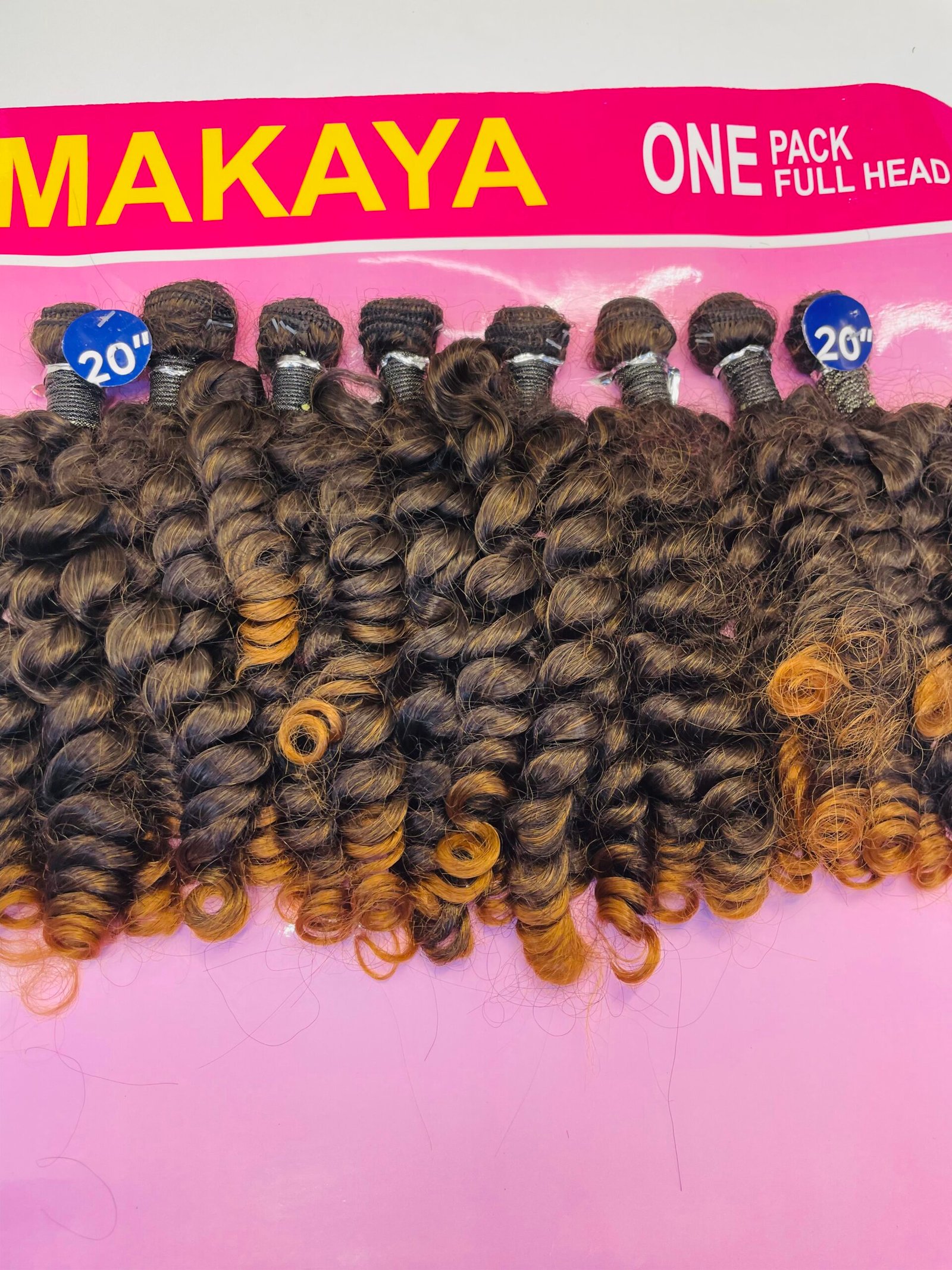 Close-up of curly brown hair extensions on a pink display board labeled 20 inches (product shot).