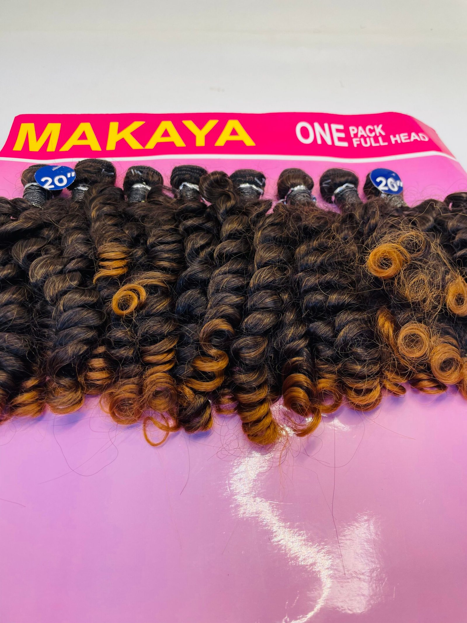 Dark curly hair extensions displayed on a pink board with MAKAYA branding and 'ONE PACK FULL HEAD' text.