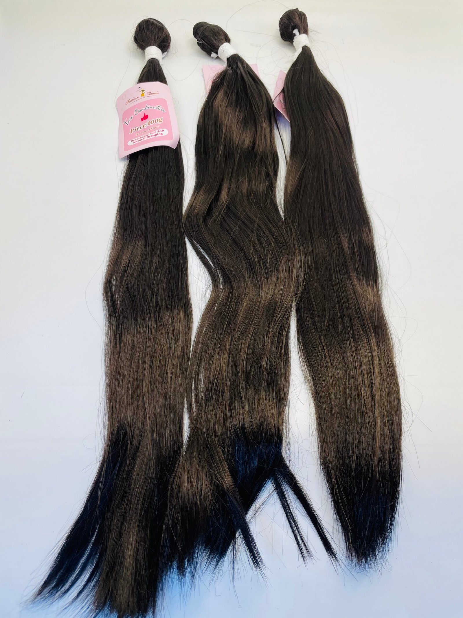 Three long dark-brown hair extensions with a pink product tag attached at the top.