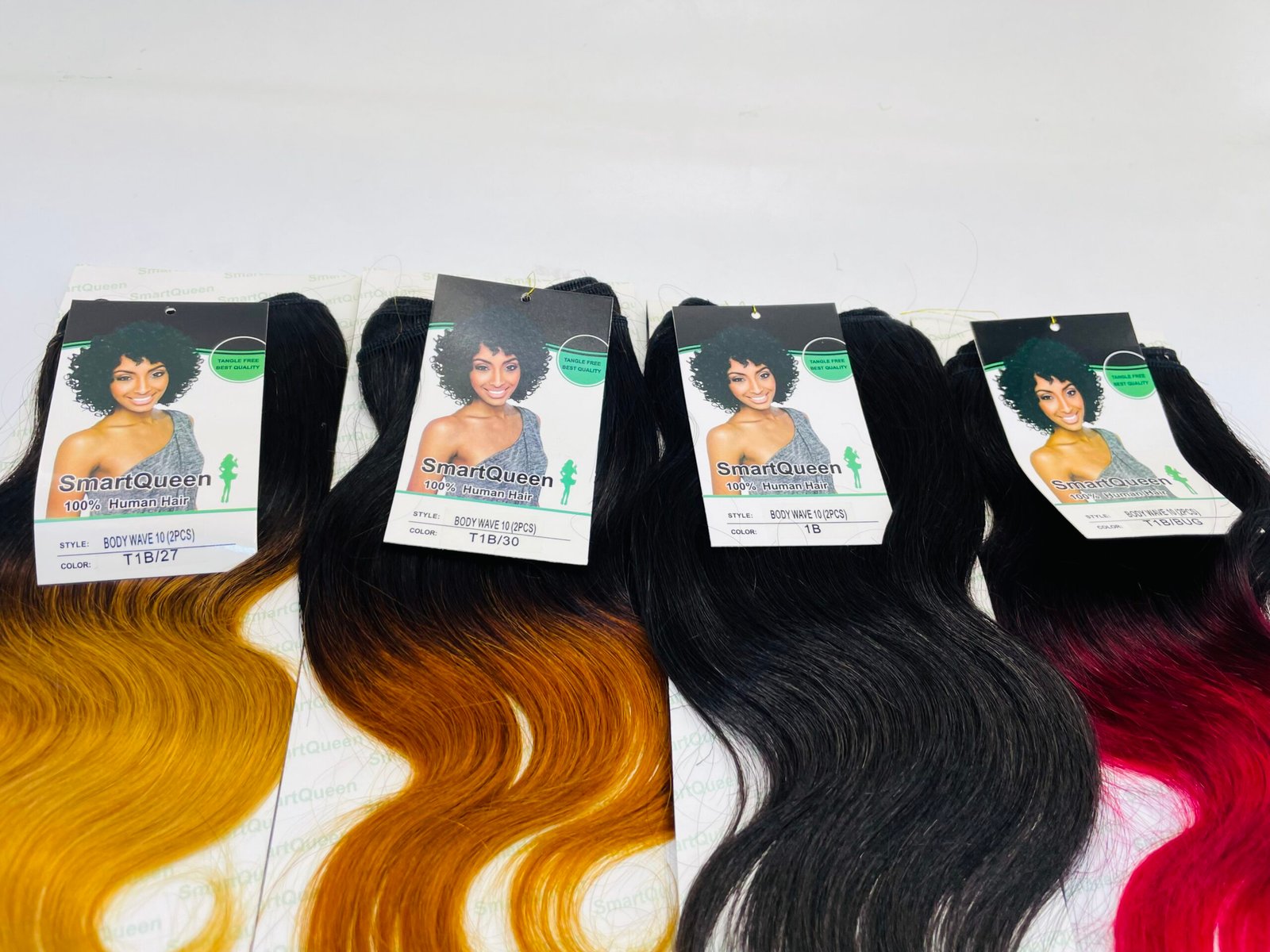 Rows of synthetic hair bundles with colorful ombre ends and SmartQueen product tags visible.