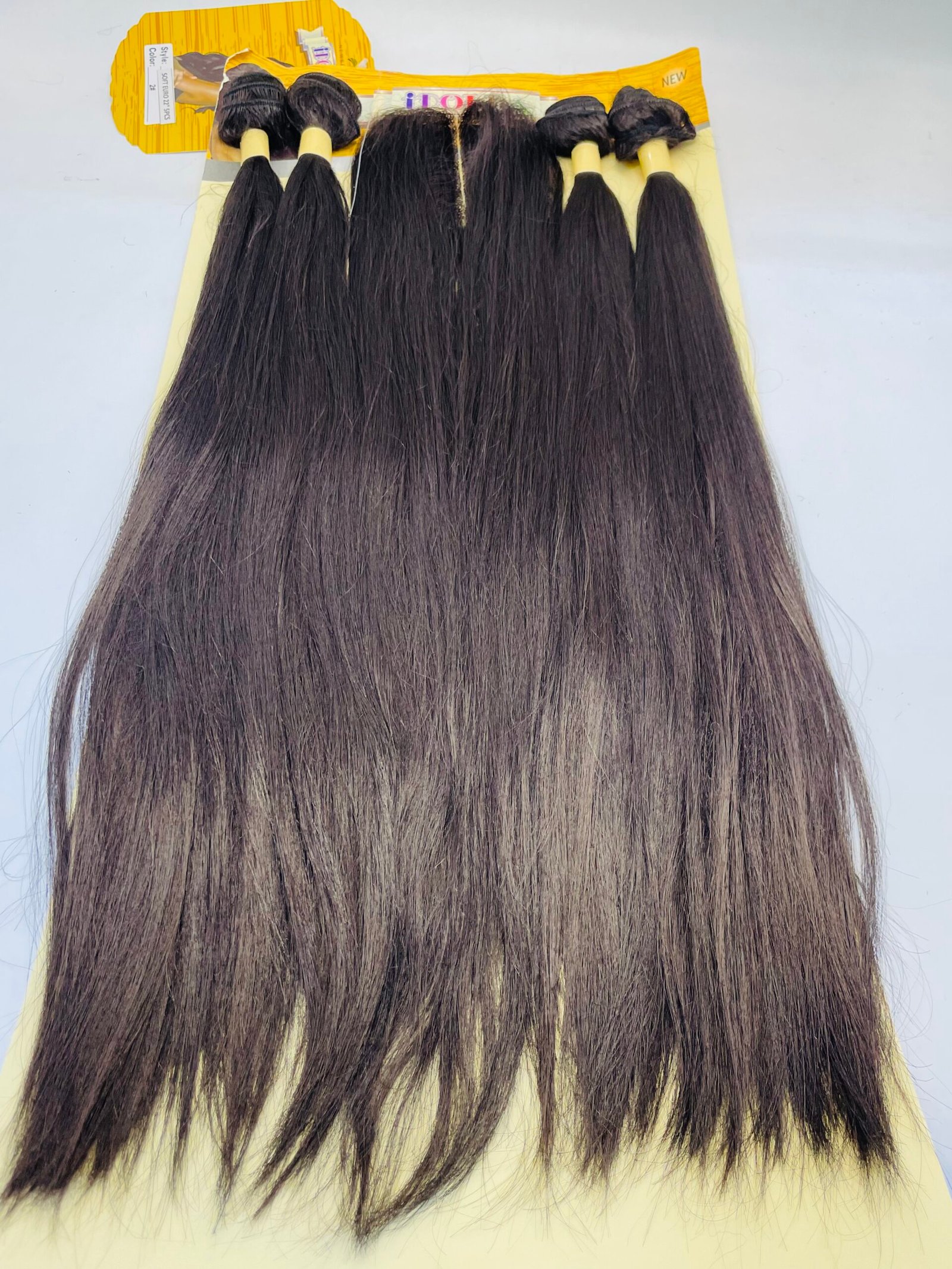 Product image of five long straight dark brown hair extension bundles attached to a yellow display card for sale, arranged side by side on a pale surface.