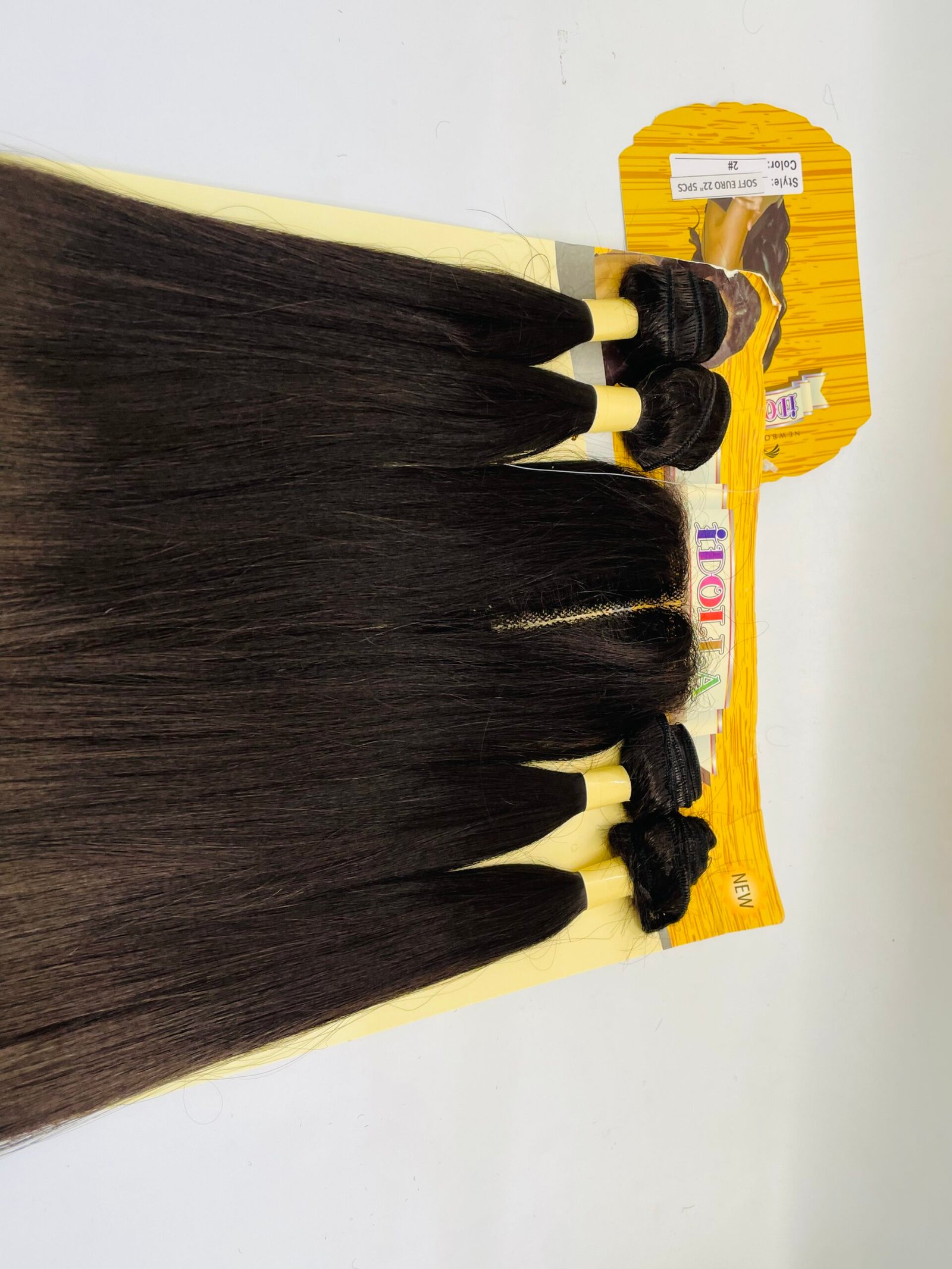 Several long, straight dark-brown hair extensions hanging on yellow display hooks