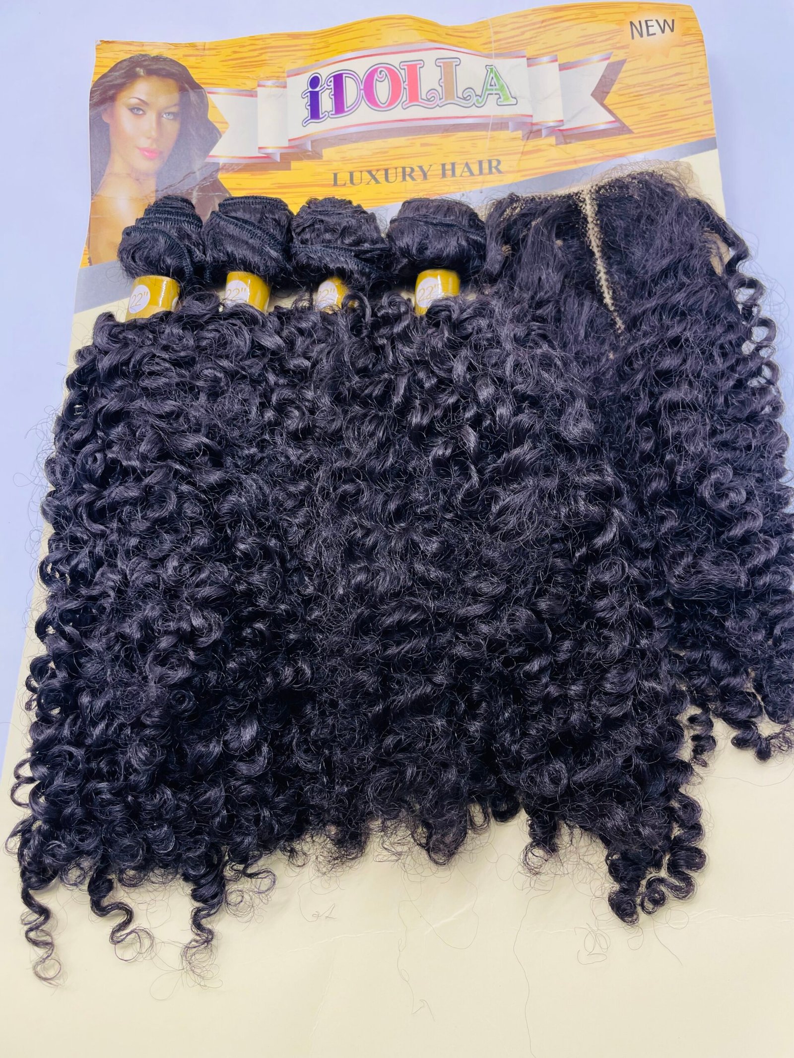 Curly black hair extensions in bundles on a yellow iDOLLA Luxury Hair packaging card.