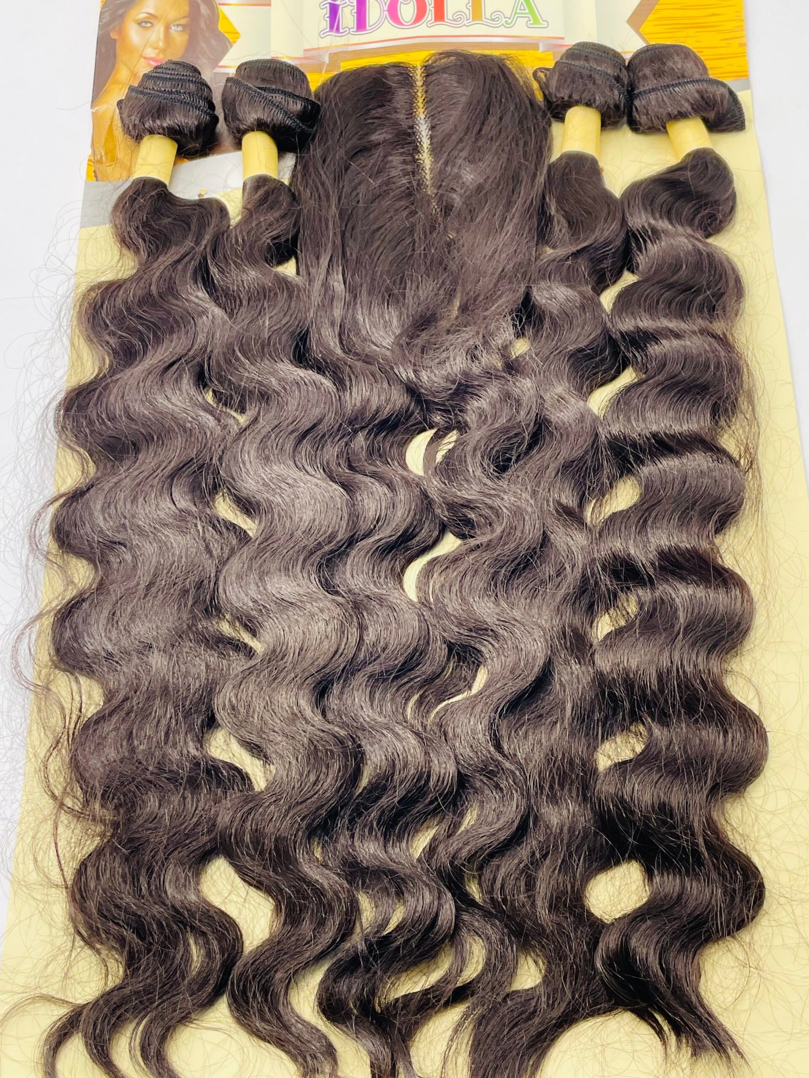 Bundle of dark brown, wavy hair extensions arranged on a yellow display card, ready for attachment