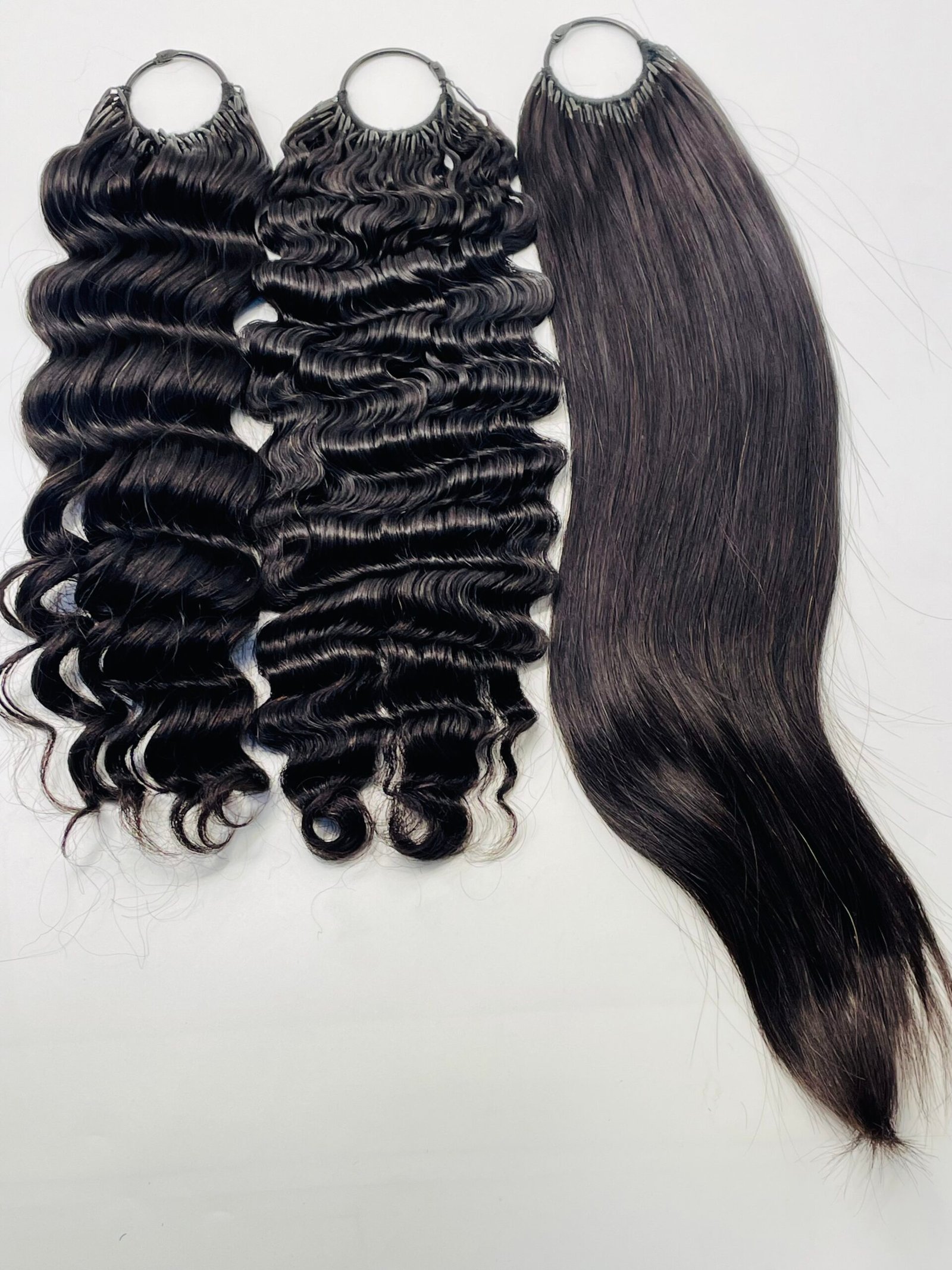 Three black hair extensions bundles: two with loose waves and one with straight, smooth texture against a light background.