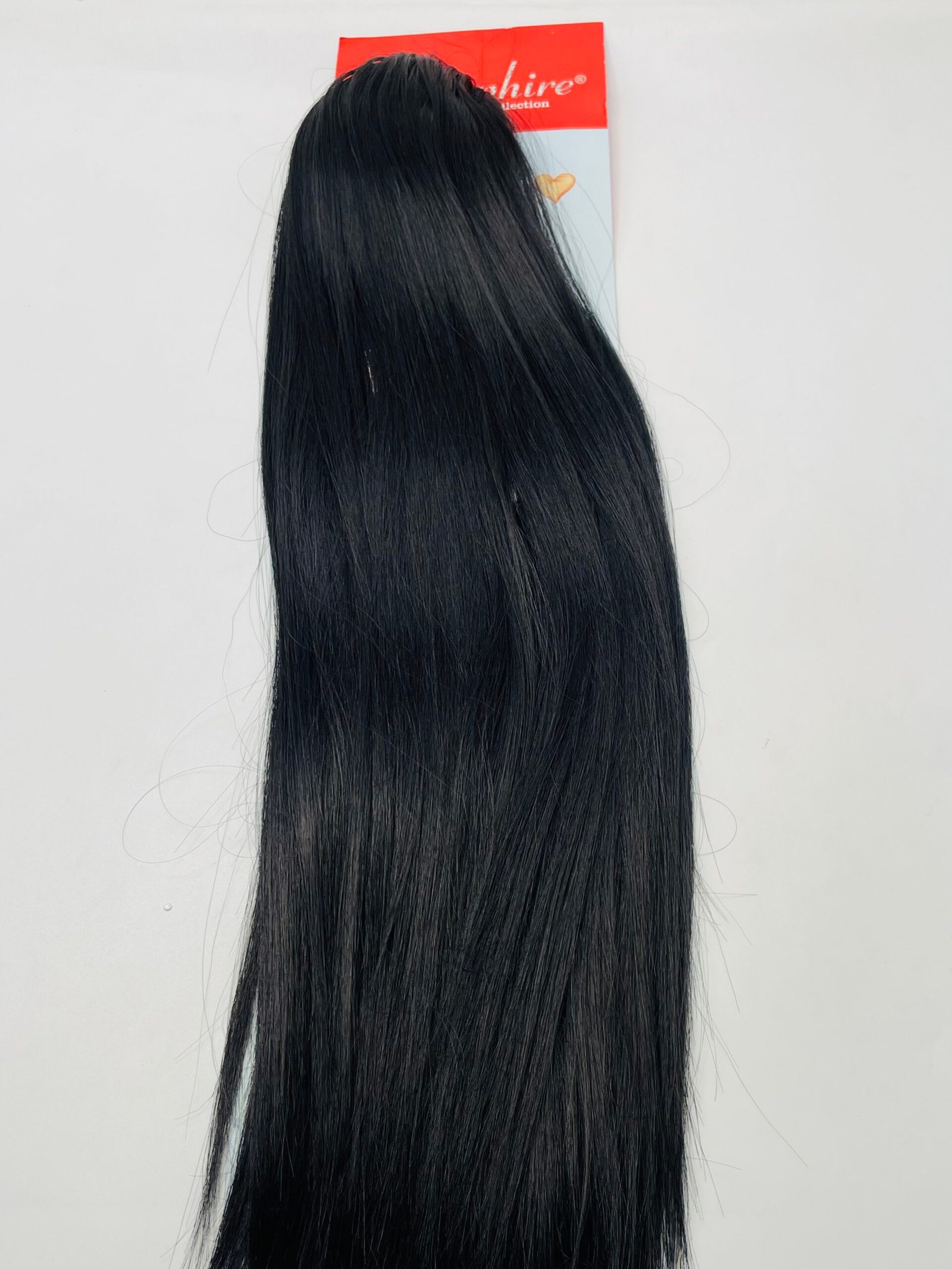Long, straight black hair extension hanging against a white background with a red product tag at the top