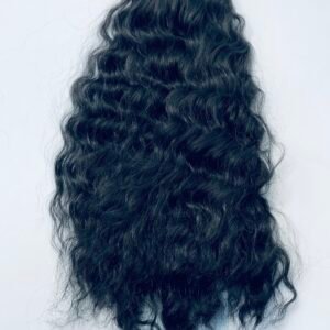 Back view of a person with long, wavy black hair; a small red square sits on top and a light blue strip with orange hearts hangs at the bottom.