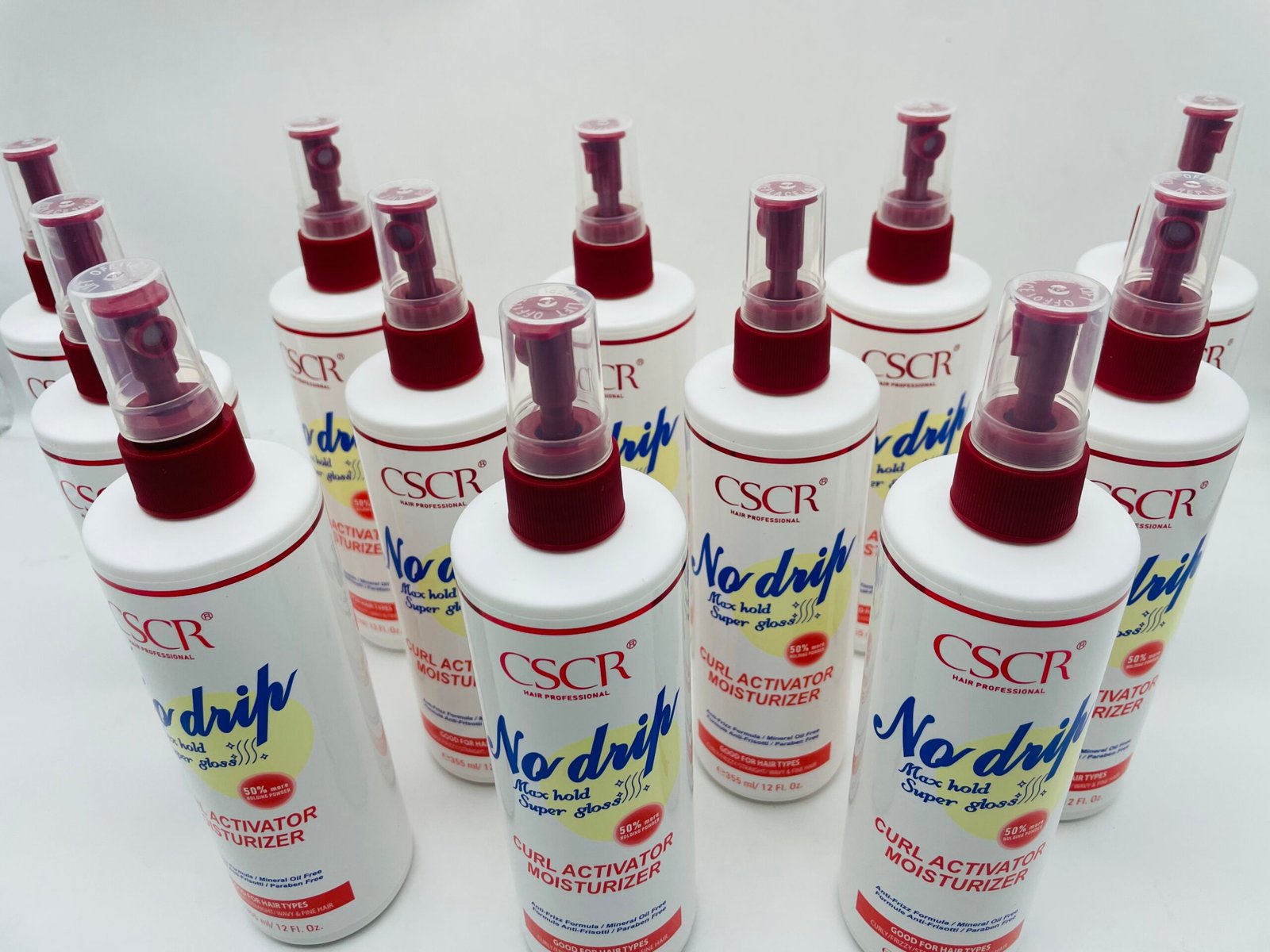 Row of white spray bottles with red nozzles arranged in a display, labeled CSCR Curl Activator Moisturizer.