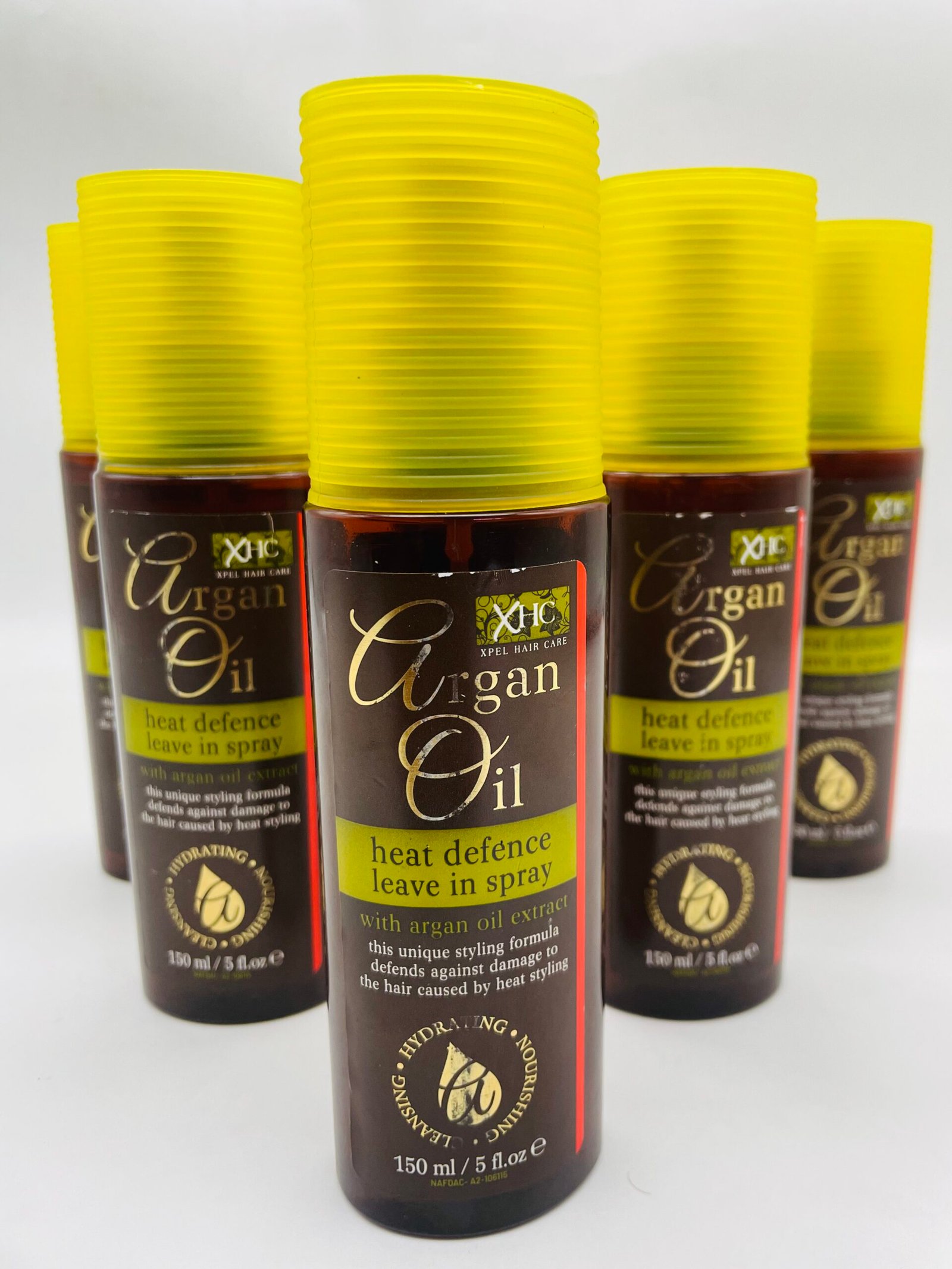 Bottles of Argan Oil heat defence leave-in spray with bright yellow caps lined up together