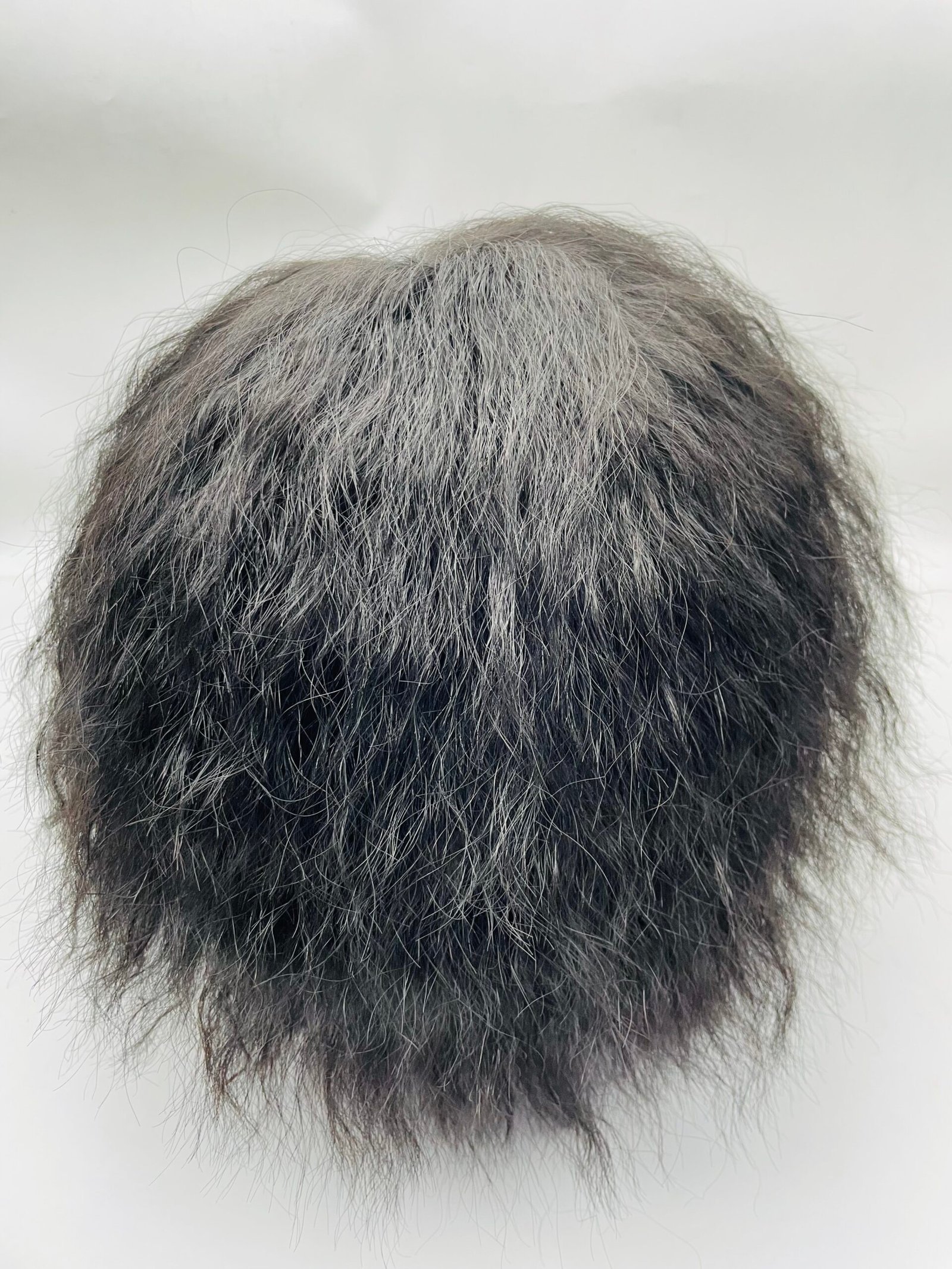 Close-up of the crown showing a mix of gray and dark hair on a head.