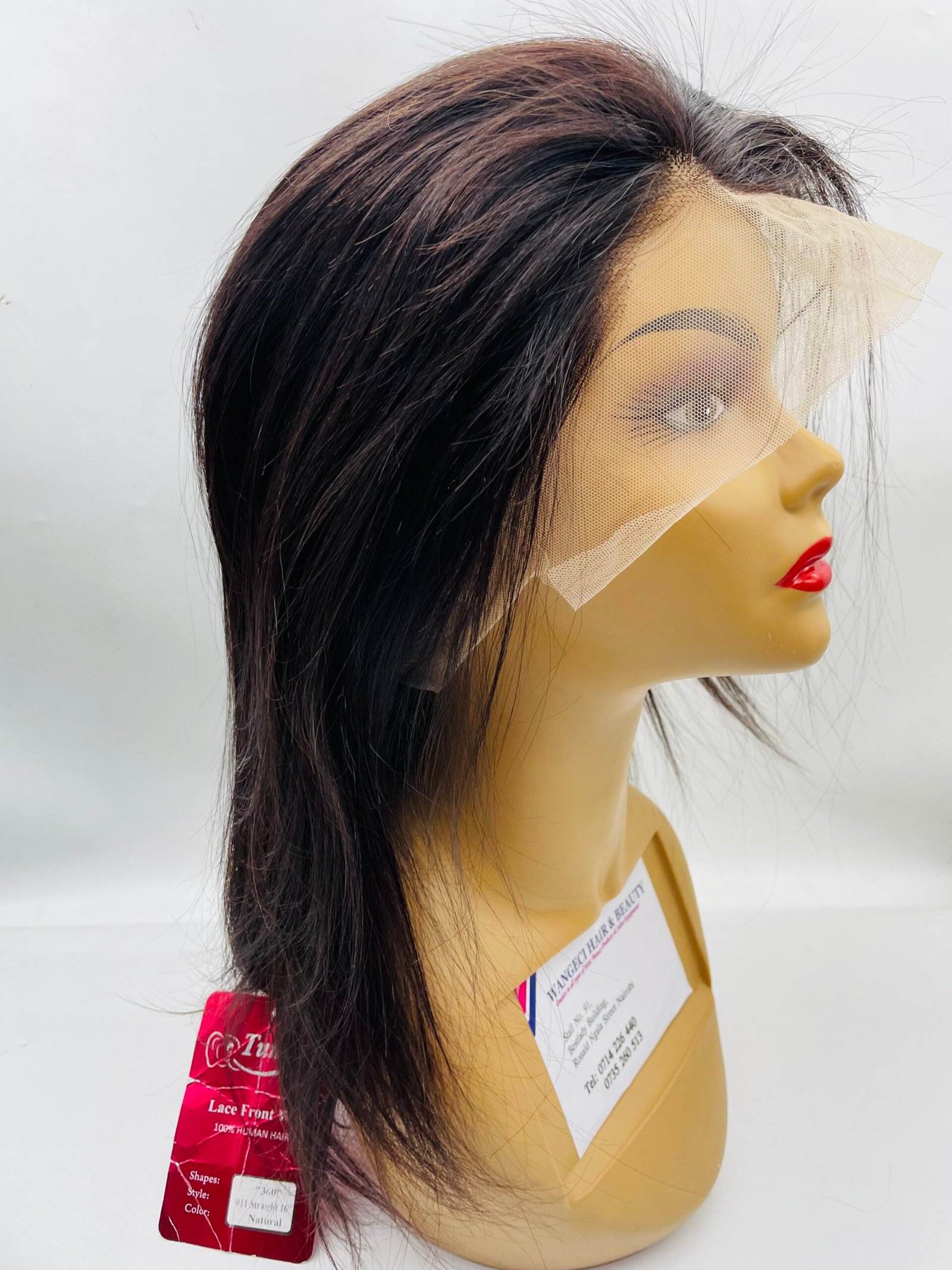 Side view of a mannequin head wearing a long dark brown wig with a beige net veil across the face.