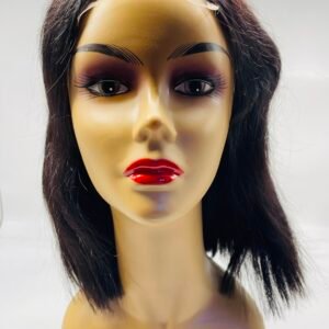 Mannequin head with a long dark brown wig and bold makeup, red lips, against a light background.