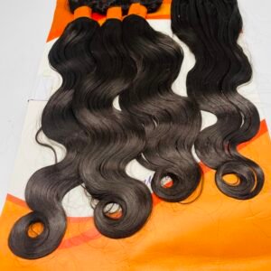 Bundles of long black wavy hair extensions laid on an orange display card.