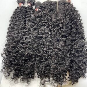 Close-up of dark curly hair extension bundles with red tags, laid on a white surface.