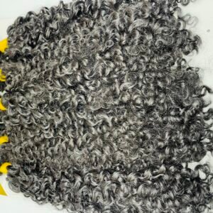 Coiled gray curly hair extensions laid on a white background with a yellow display card visible on the side, suggesting a product photo.