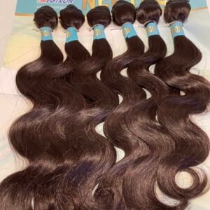 Six dark brown wavy hair extensions with blue weft labels laid on a surface, Megtron backdrop visible.