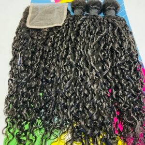 Close-up of glossy black curly hair extensions displayed on a colorful poster board backdrop.