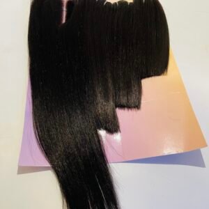 Long, shiny black hair extension laid over a pastel pink packaging card with a blunt cut fringe at the top image edge.